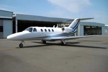 Location jet privé : Jet privé devant hangar, ciel bleu.