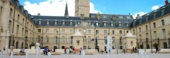 **Texte original :**
Les gens se promènent près d'un bâtiment historique avec une tour d'horloge et une cour ornée de fontaines, sous un ciel bleu, à Dijon Bourgogne. C’est le cadre idéal pour ceux qui arrivent par location de jet privé.

**Nouveau texte :**
_Dijon Bourgogne_, promenade près du bâtiment historique.