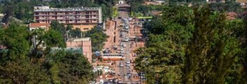 Rue animée de Kampala avec collines et ciel dégagé.