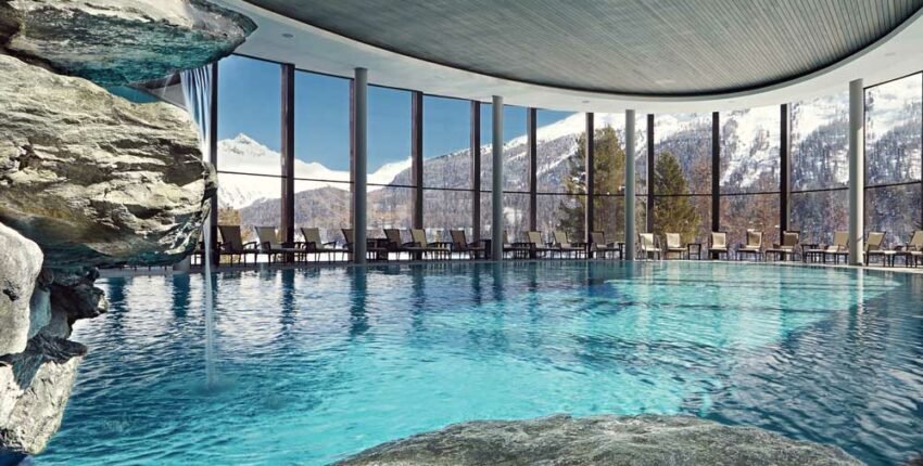Piscine intérieure avec vue sur montagnes enneigées.