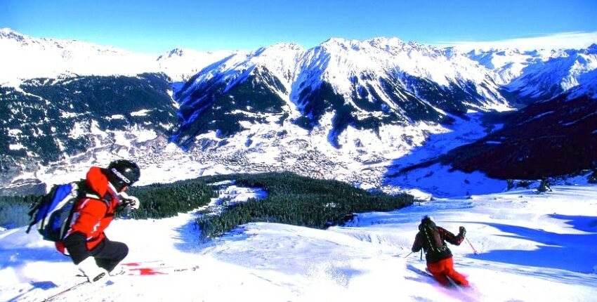 Deux skieurs dévalent une montagne enneigée.