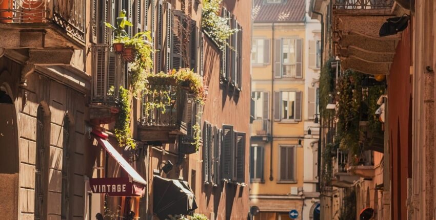 Milan Linate, rue ensoleillée avec motos et balcons.