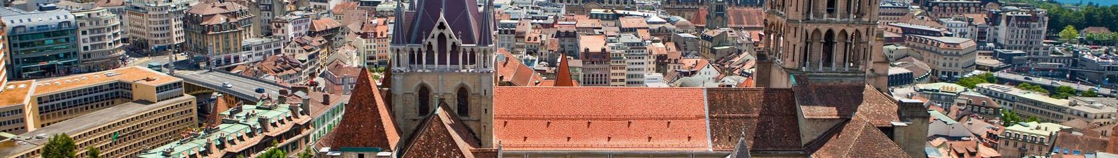 Vue aérienne Cathédrale de Lausanne, toits rouges, lac, montagnes.
