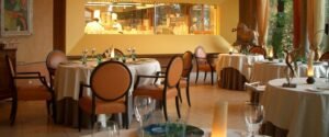 Restaurant Hôtel Albereta, tables rondes et vue cuisine.