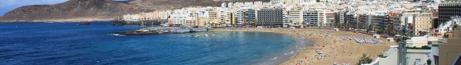 Las Palmas Gran Canaria plage bondée, eau bleue, montagnes.