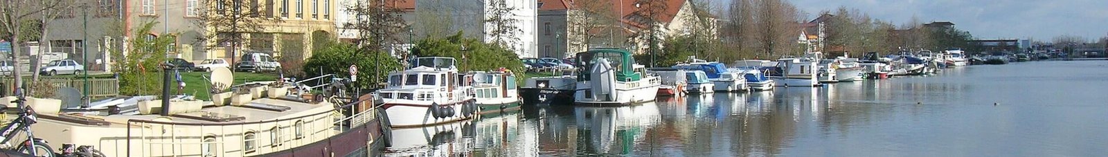 Vue panoramique Roanne, rivière calme, bateaux à quai, journée ensoleillée.
