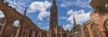 Ruines de la cathédrale de Coventry, ciel bleu, personnes assises.