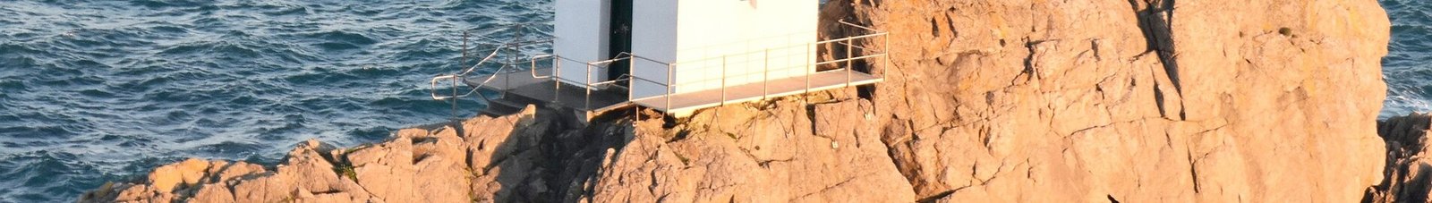 Guernesey : Petit bâtiment blanc sur la côte rocheuse.