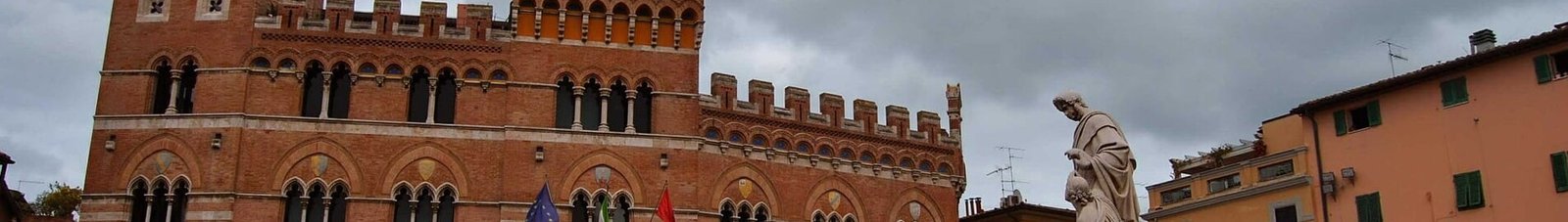 Grosseto, bâtiment historique avec statue et drapeaux.