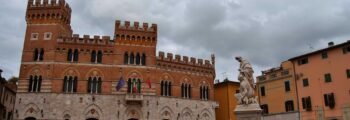 Grosseto, bâtiment historique avec statue et drapeaux.