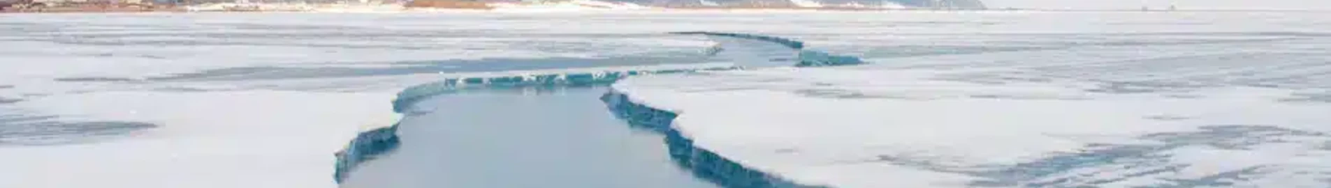 Glace craquelée sur un lac gelé avec des montagnes enneigées sous un ciel nuageux au loin, rappelant les paysages pittoresques près d'Irkutsk. - GCD Logistique Aviation